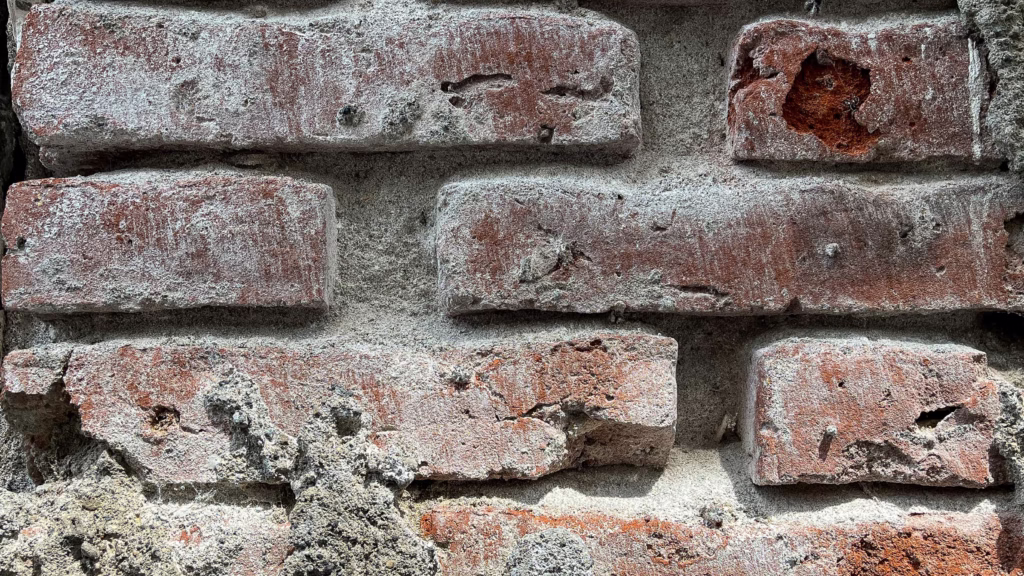 Extreme close-up of weathered red bricks with crumbling mortar joints and spalling damage, highlighting the need for professional brick repair and restoration in Jacksonville, FL.
